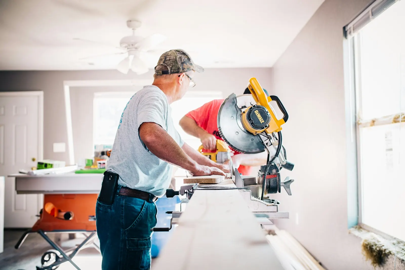 Two carpenters cutting trim at a mitre saw
