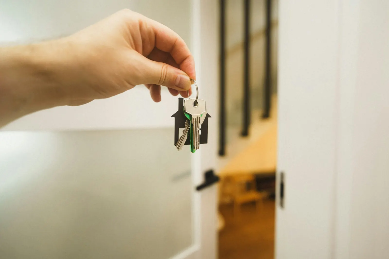 A hand holding out a set of door keys in a hallway