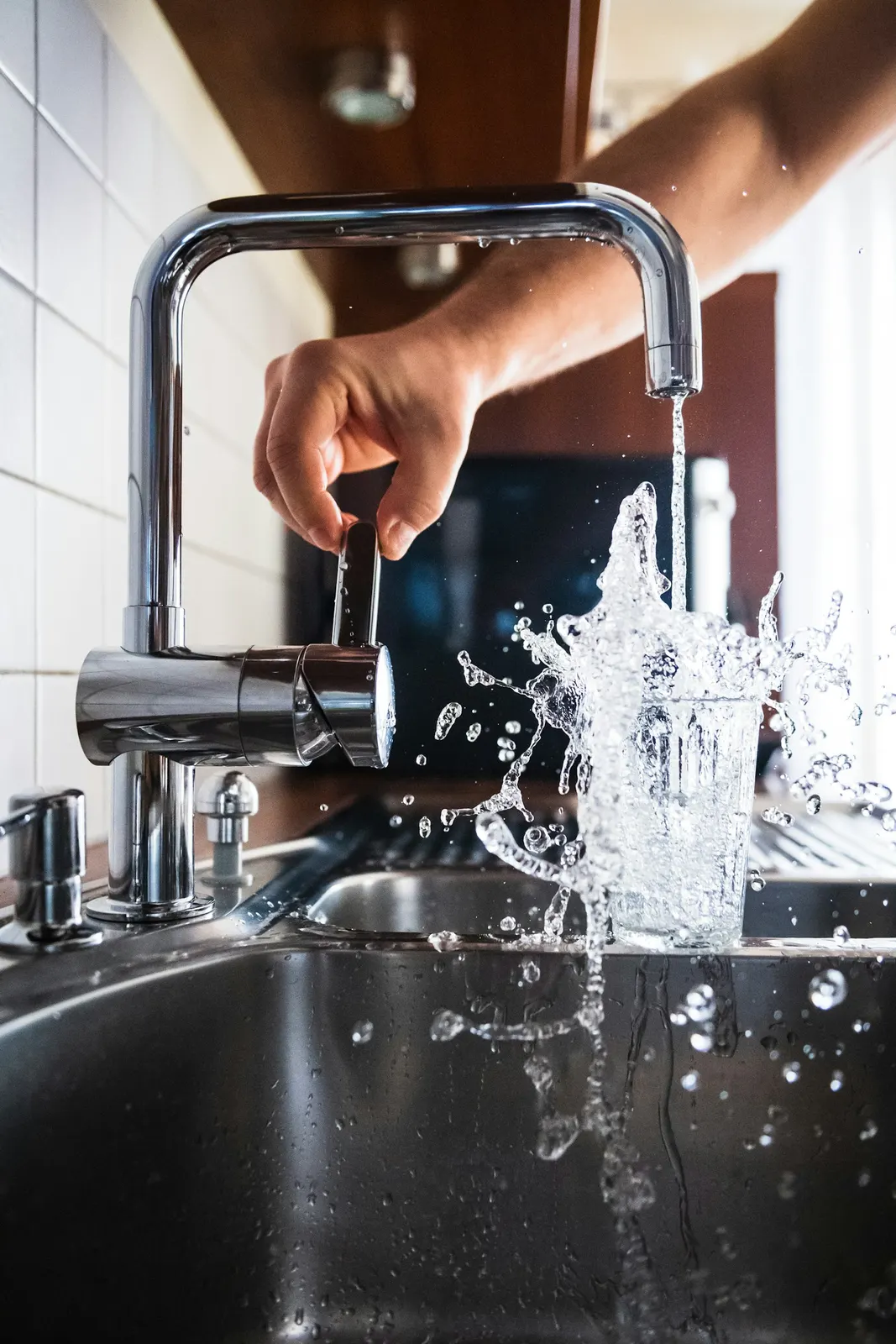 A hand turning on a kitchen tap