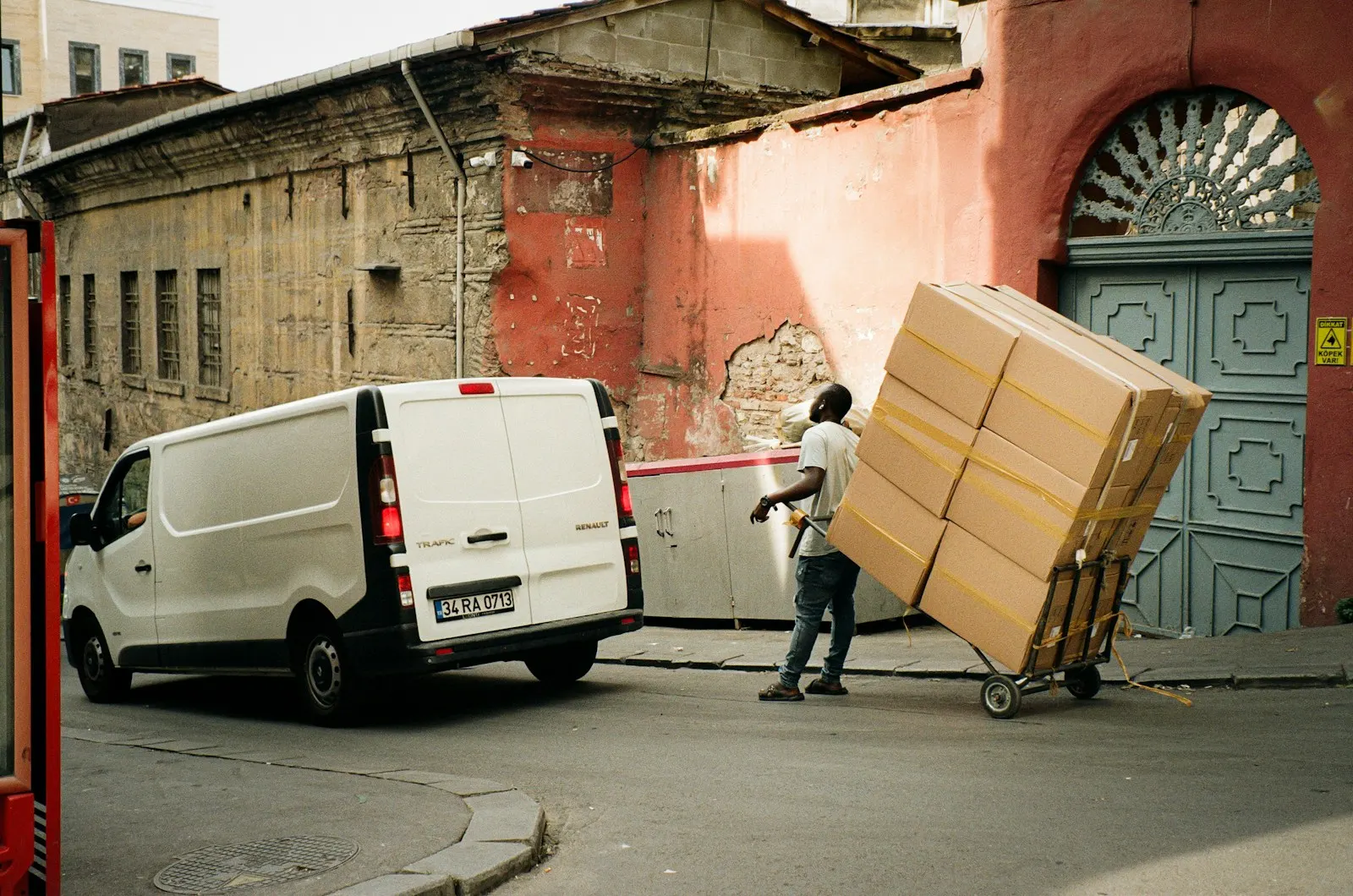 A mover wheeling stacked boxes on a dolly beside a van