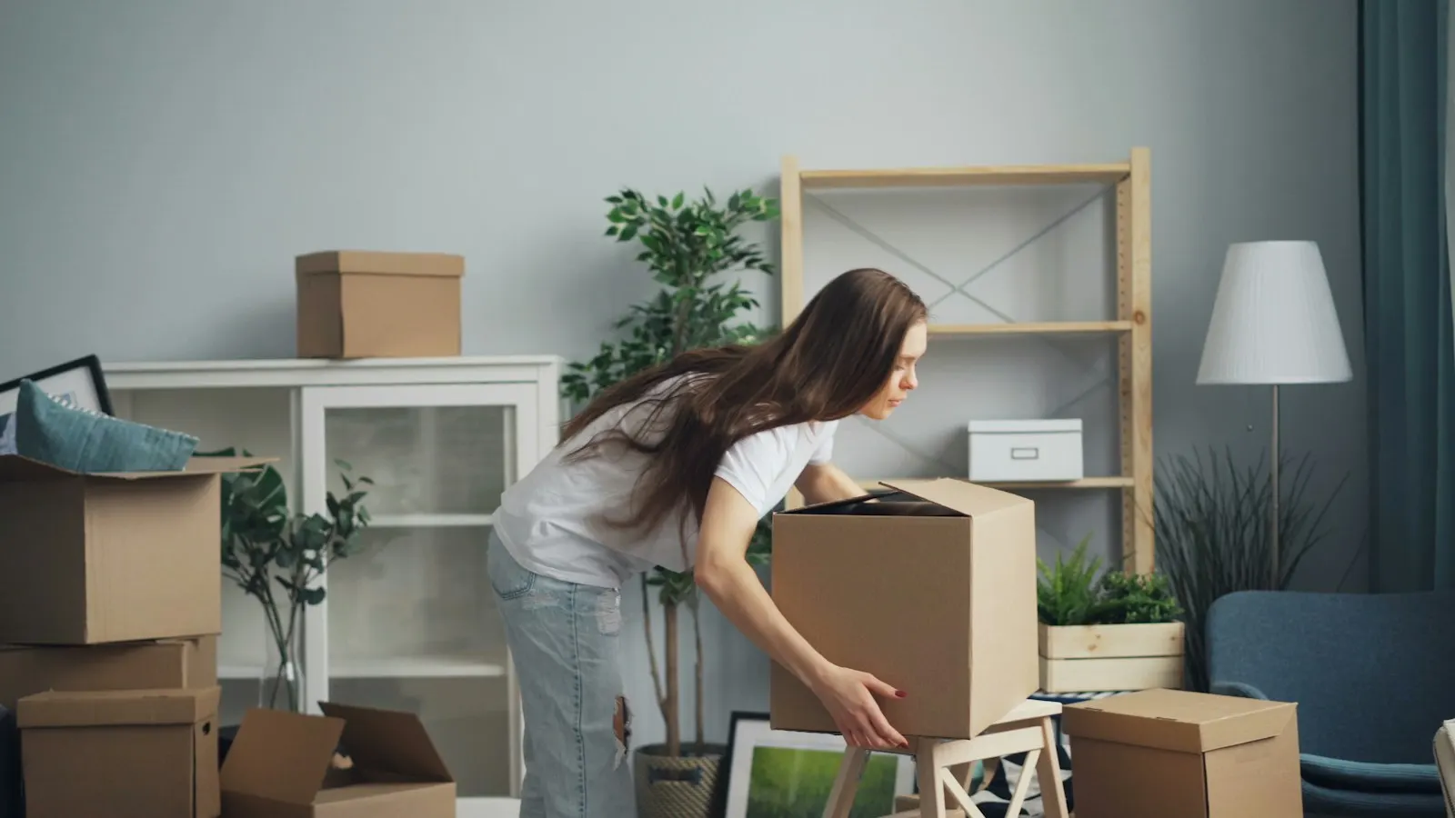 A person packing cardboard boxes in a living room