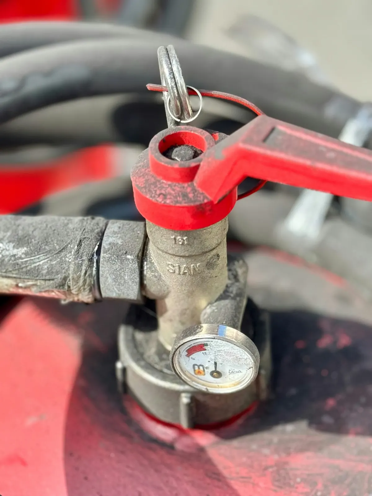 A red water valve with a pressure gauge