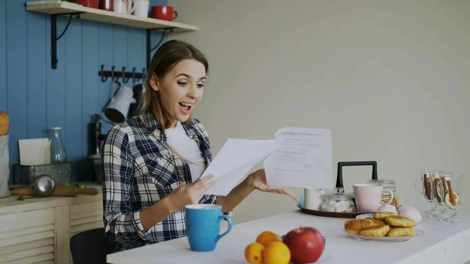 A woman reading a letter at her kitchen table